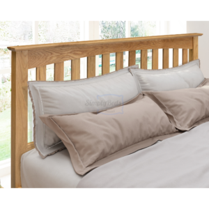 Gladstone solid oak bed with close up on the headboard which has bedding and pillows