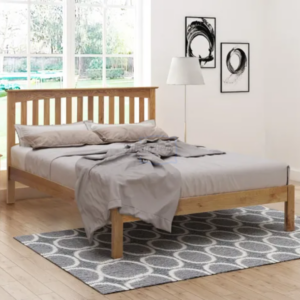 Angle picture of the Gladstone solid oak bed frame with a mattress dressed in bedding and pillows